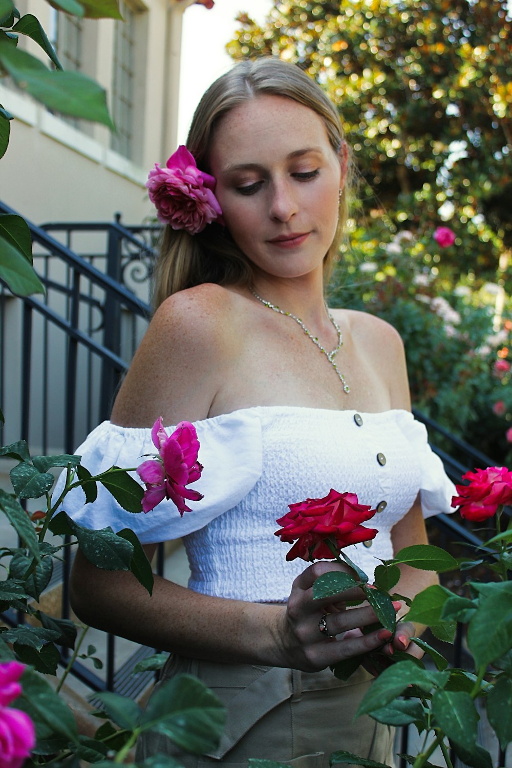 a woman in a white top is holding flowers