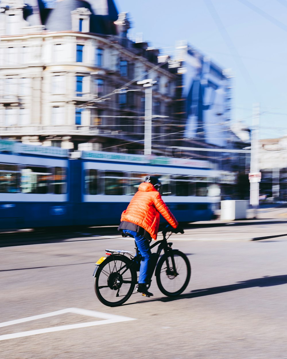 a man riding a bike down a street next to a train