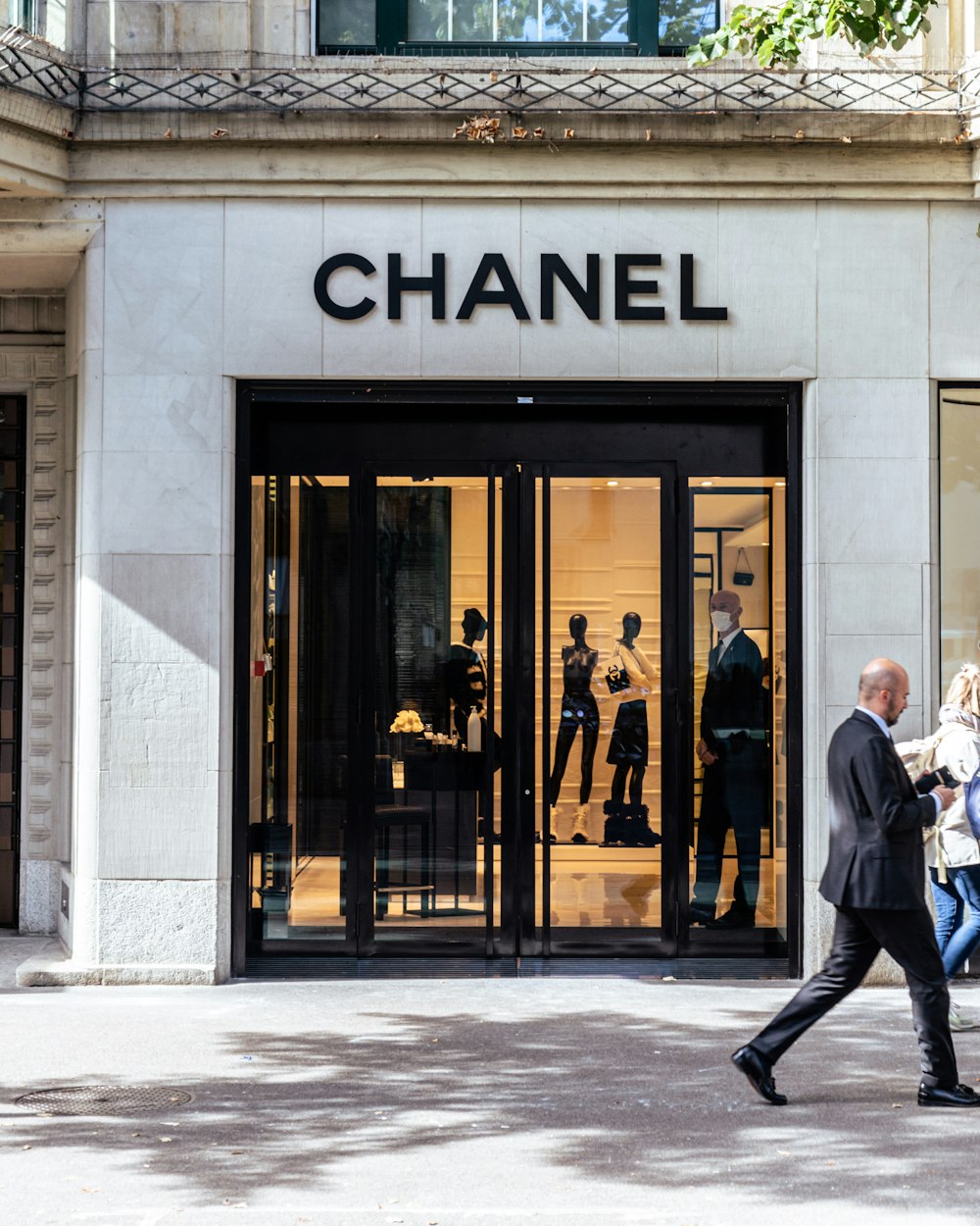 a man and woman walking past a chanel store