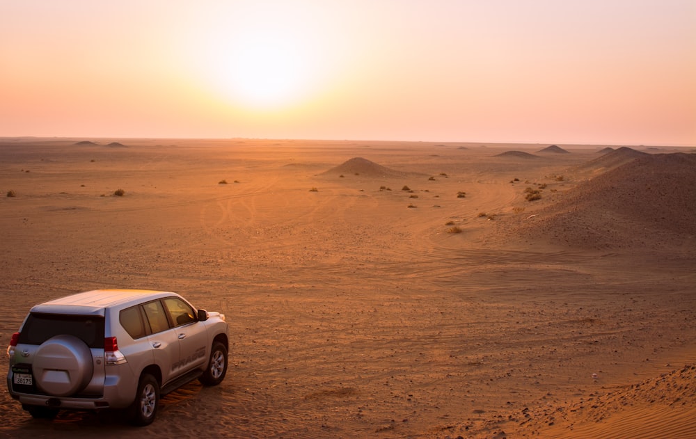 a car is parked in the desert at sunset