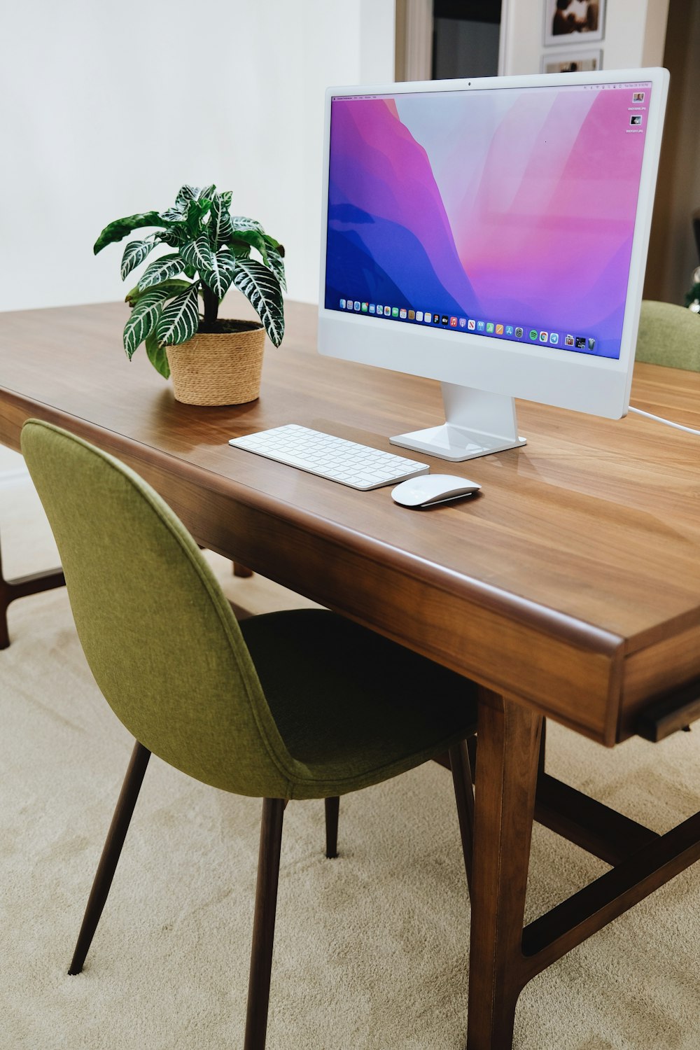 a desk with a computer and a potted plant