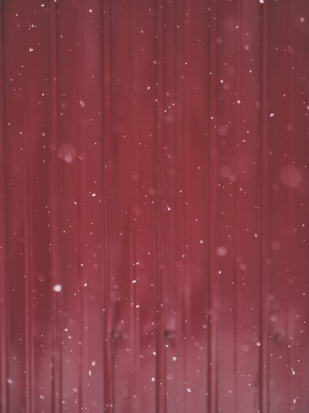 a red wall with snow falling on it