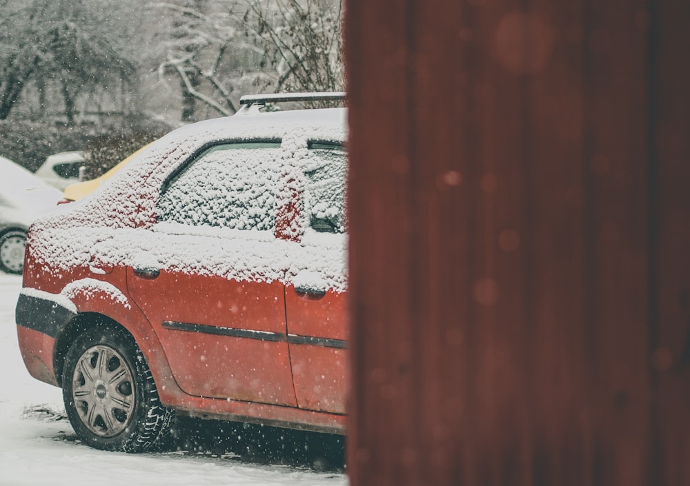 a red car is parked in the snow