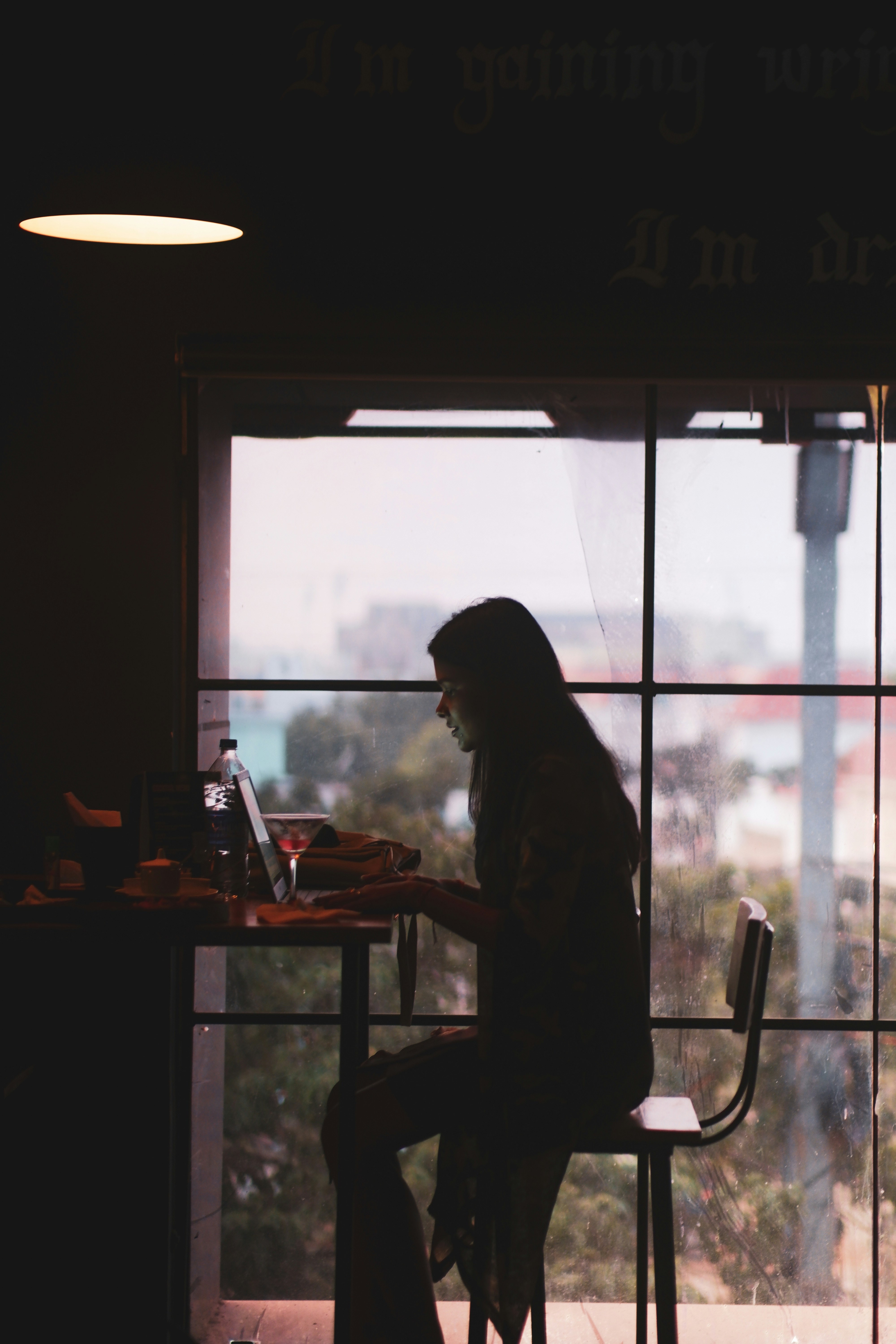 a person sitting at a table in front of a window