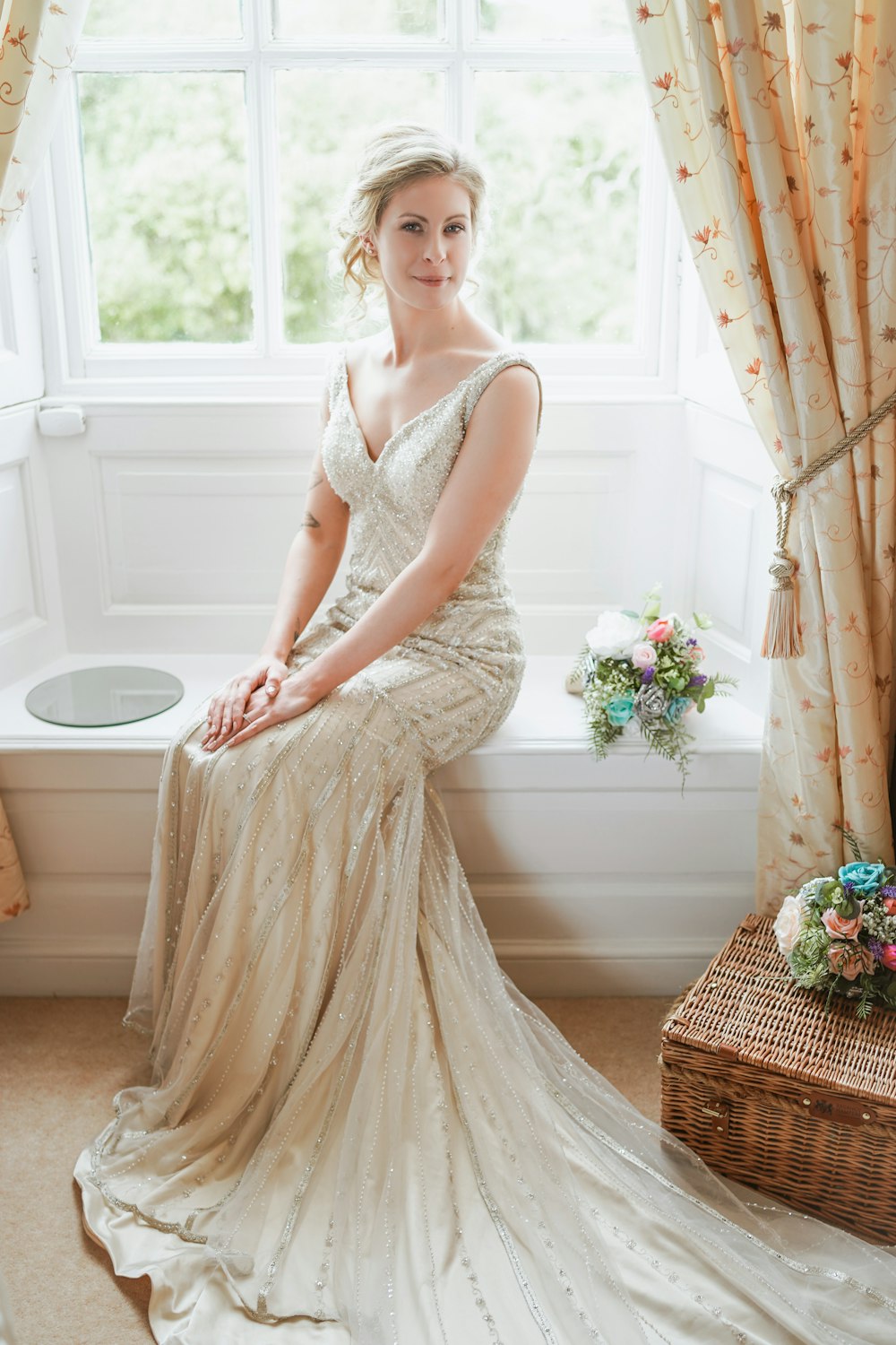 Eine Frau im Brautkleid sitzt auf einer Fensterbank