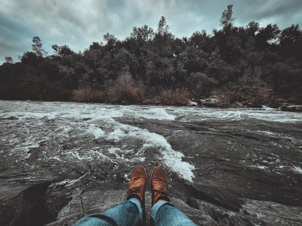 a person standing on top of a rock next to a river