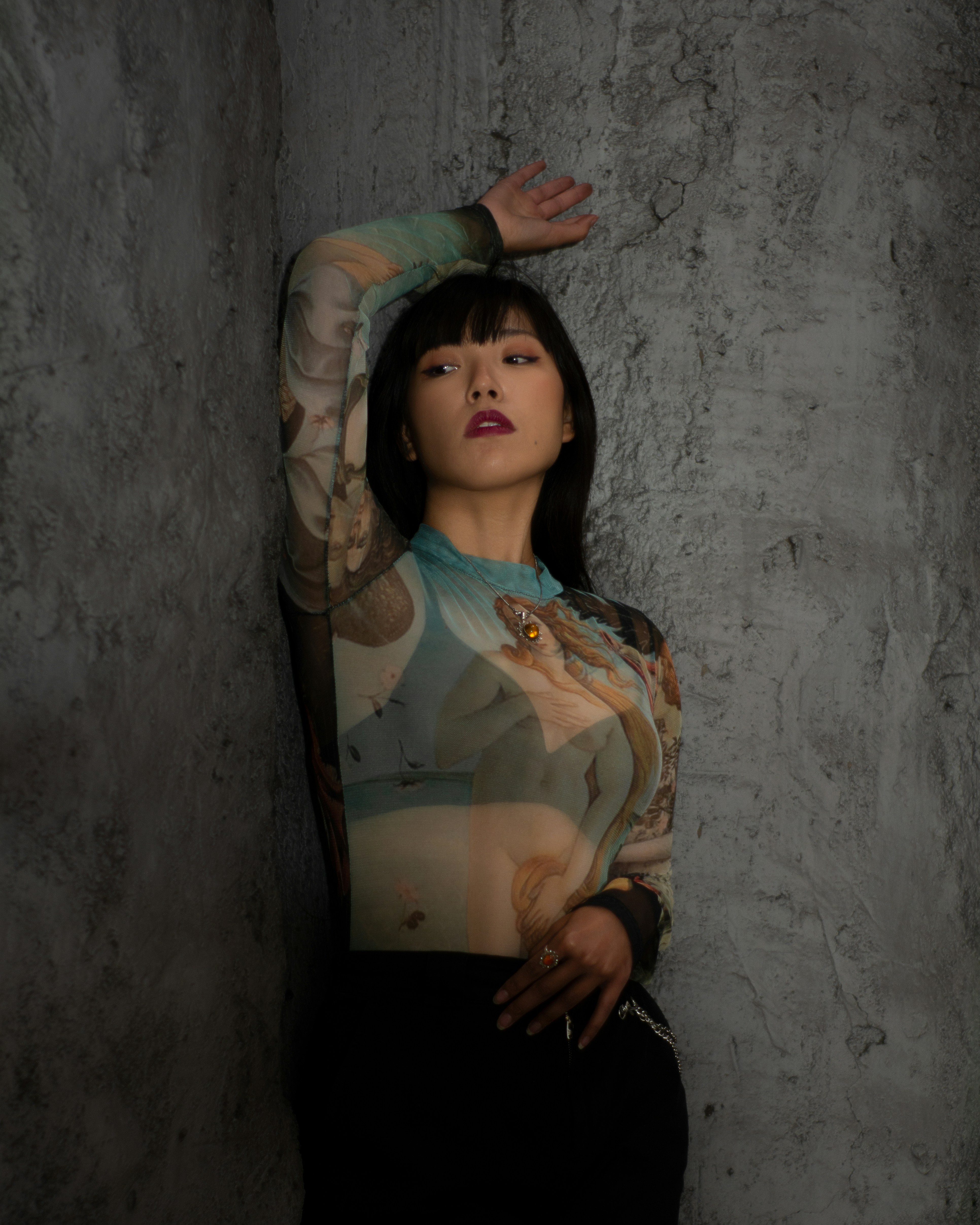 頭に手を当てて壁にもたれかかっている女性