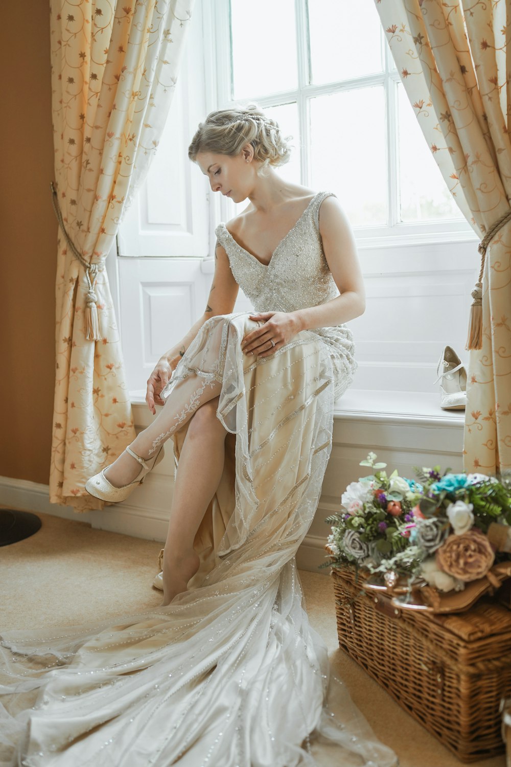 a woman in a wedding dress sitting on a window sill