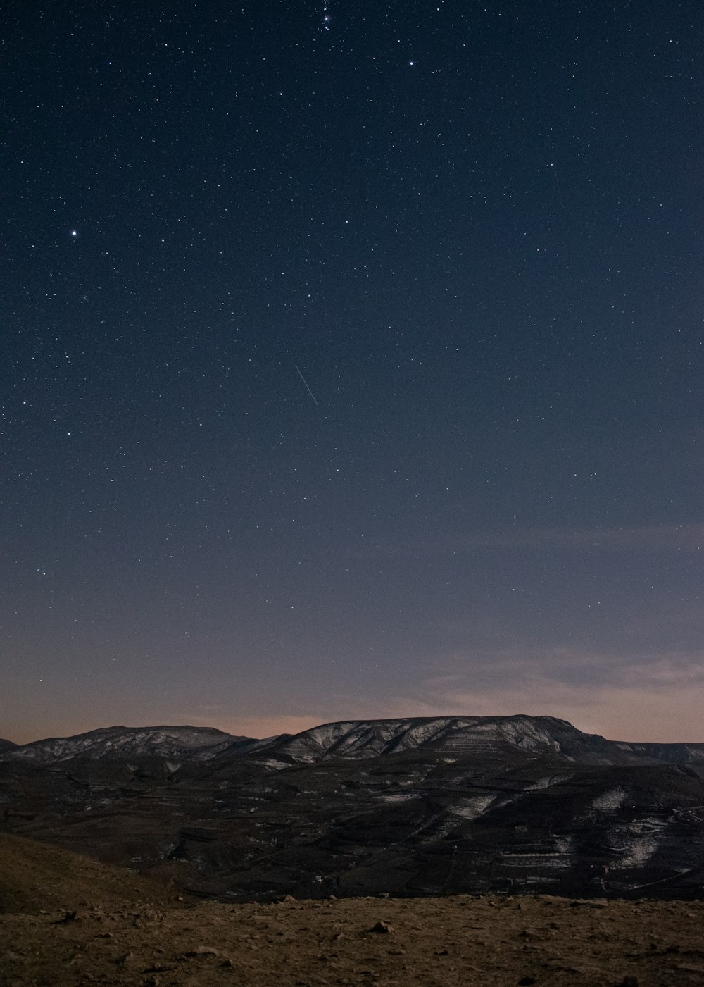 the night sky with stars above a mountain range