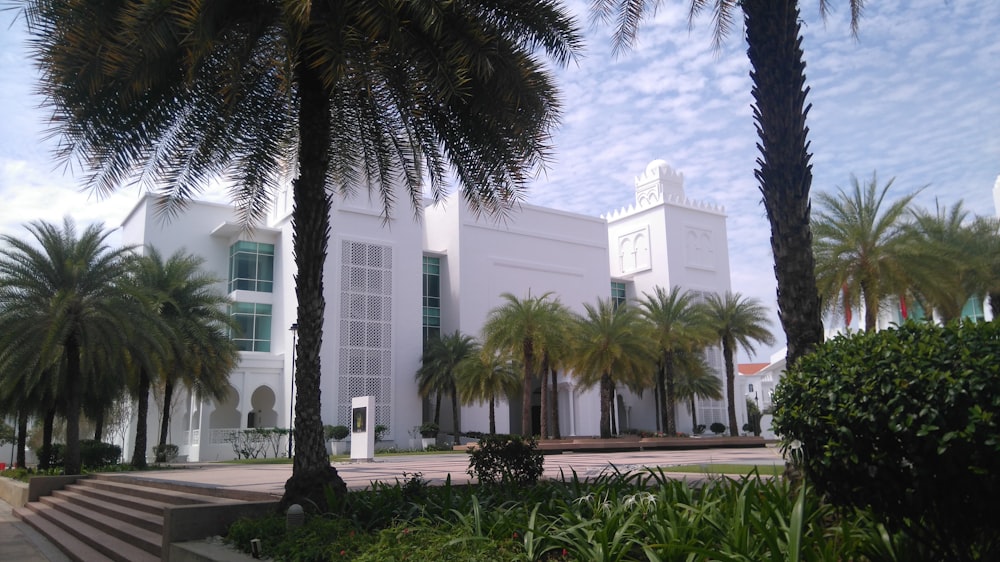 a large white building with palm trees in front of it