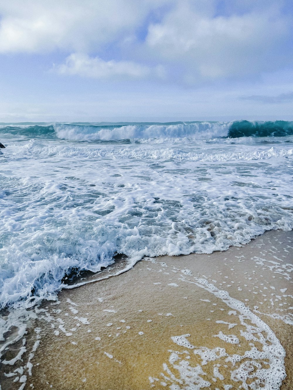 a sandy beach with waves coming in to shore