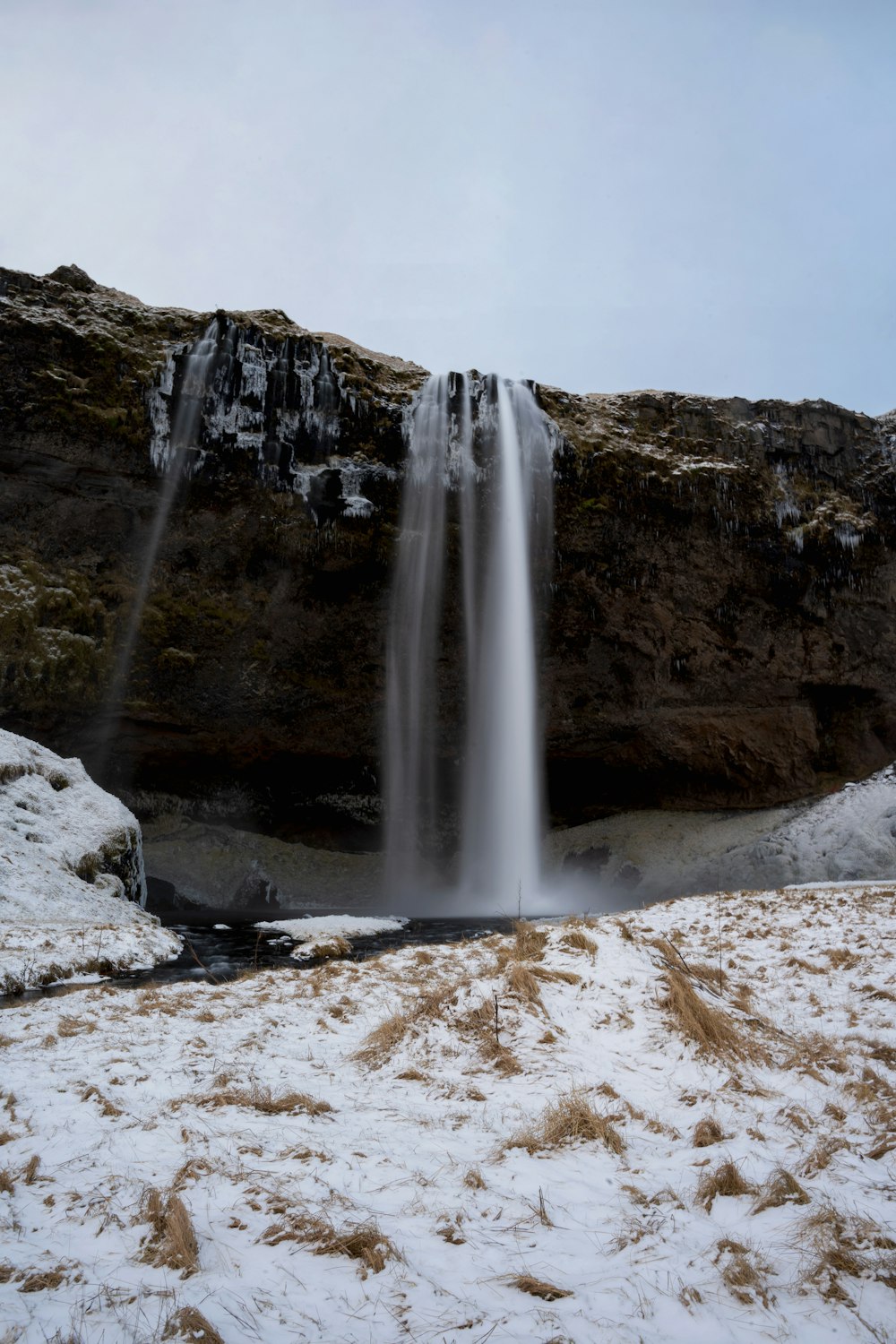 a very tall waterfall in the middle of a snowy field