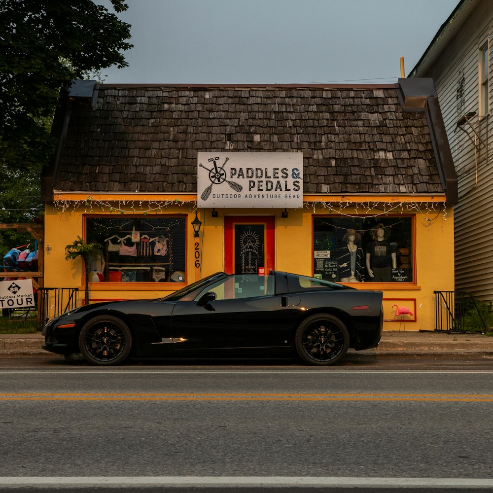 a black car parked in front of a yellow building