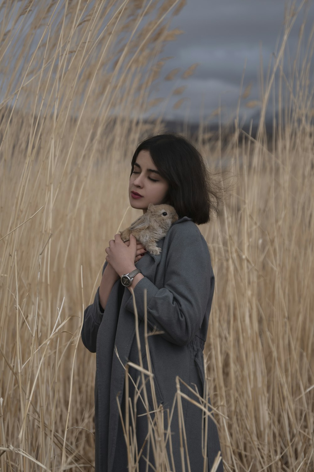 a woman standing in a field holding a teddy bear