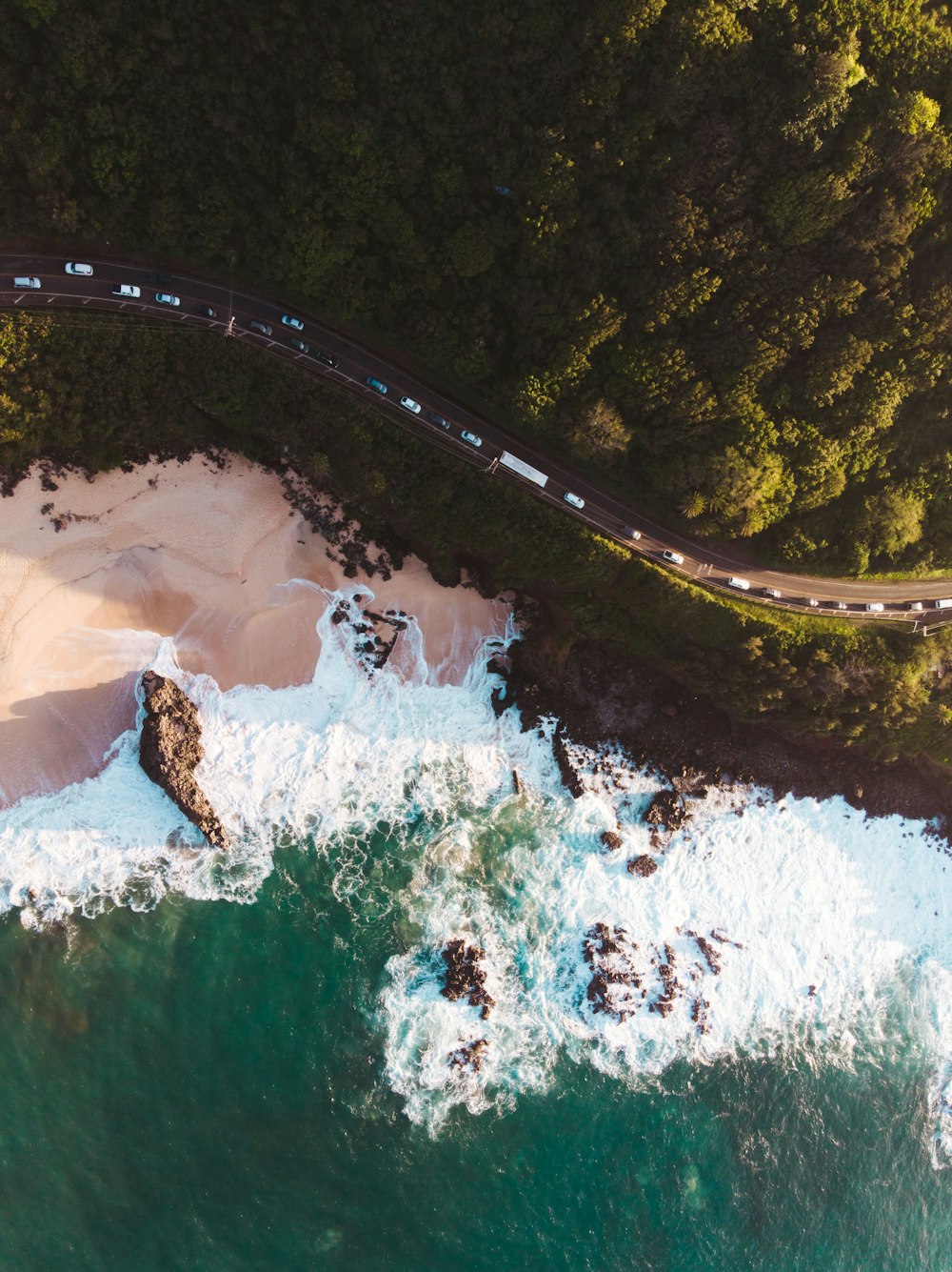 an aerial view of the ocean and a road