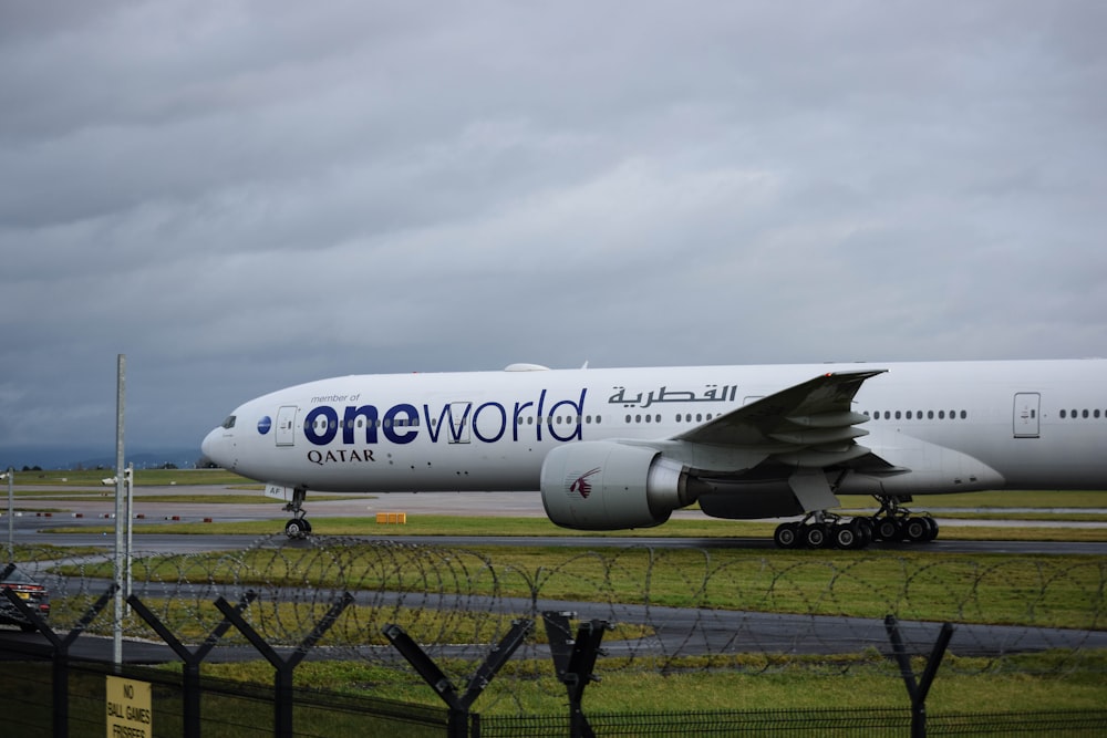a one world airplane on the runway at an airport