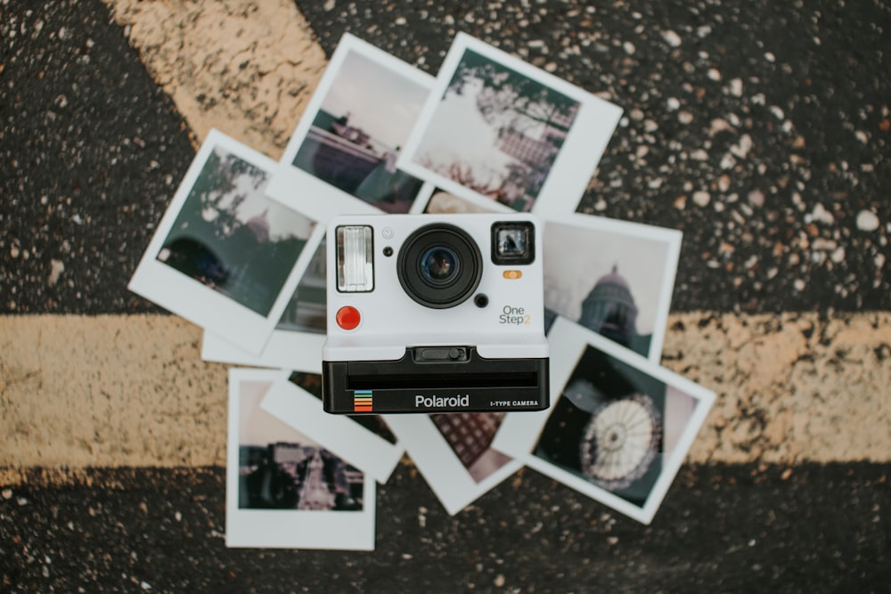 a polaroid camera sitting on top of a pile of polaroid pictures