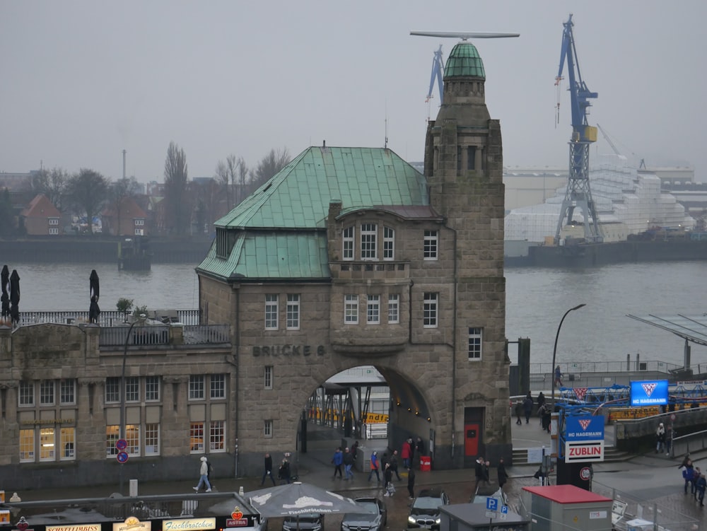 a large building with a green roof next to a body of water