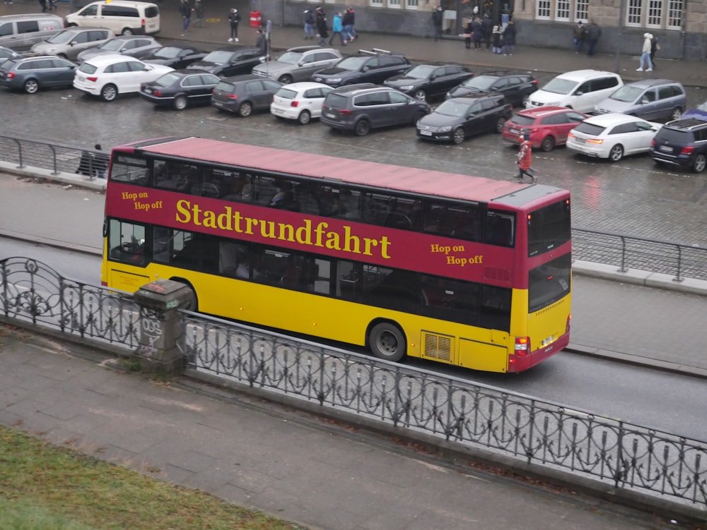 a yellow and red double decker bus driving down a street
