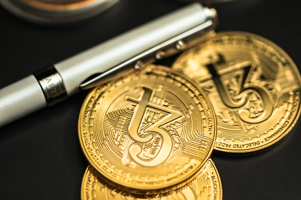 a pen sitting on top of a pile of gold coins