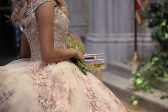 a woman in a ball gown holding a bouquet of flowers