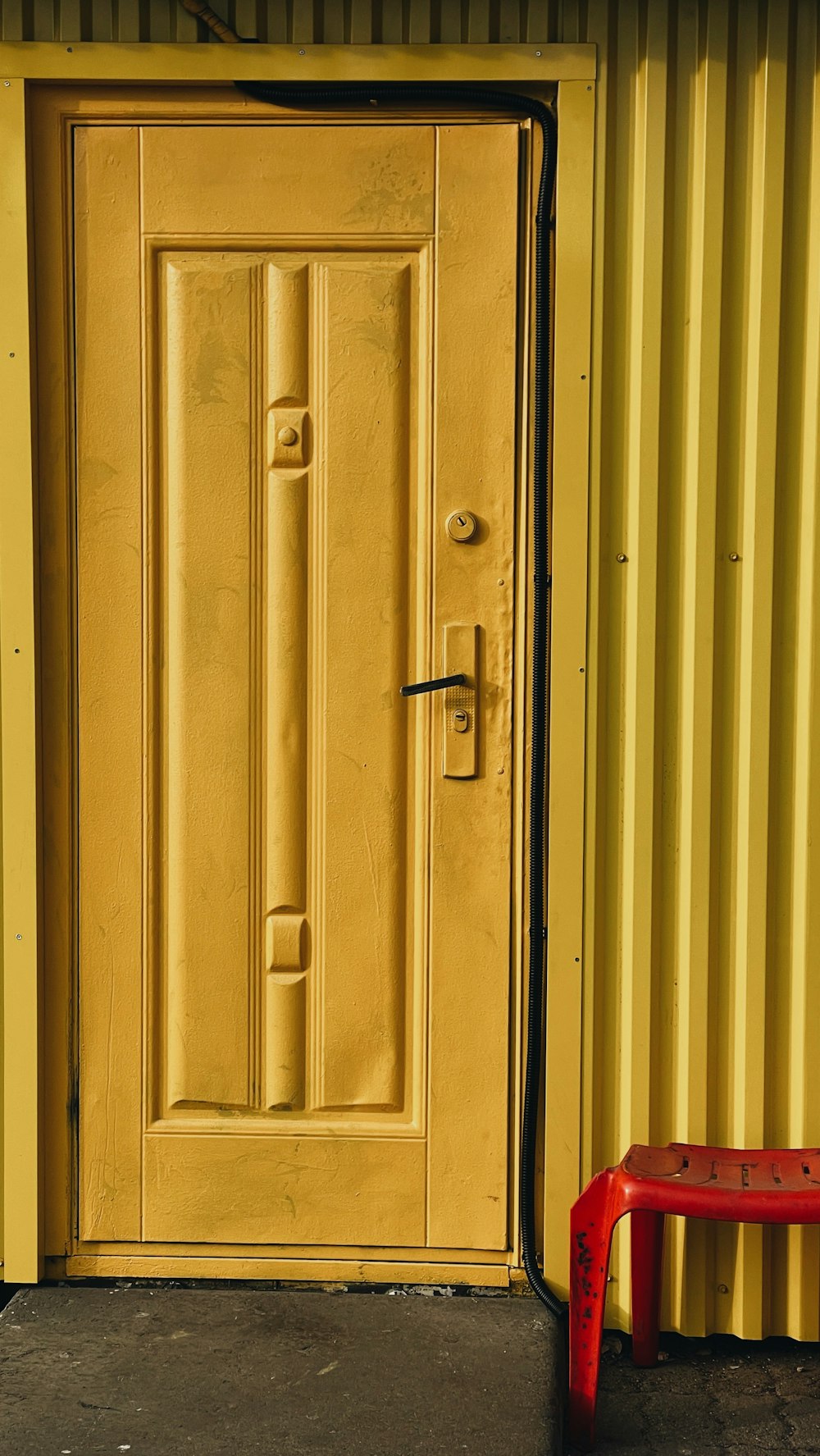 a yellow door with a red bench in front of it