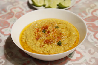 A warm, inviting bowl of dal moong garnished with fresh coriander and a slice of lemon on a rustic wooden table.