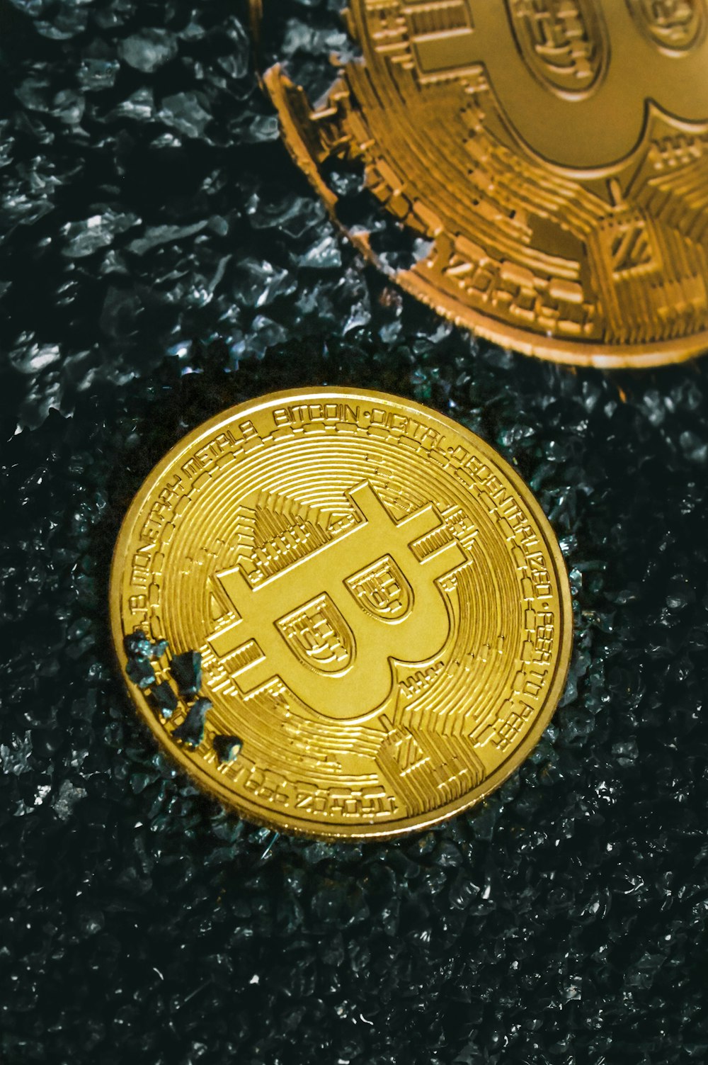 two gold bitcoins sitting side by side