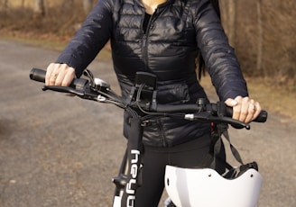 a woman standing next to a bike on a road