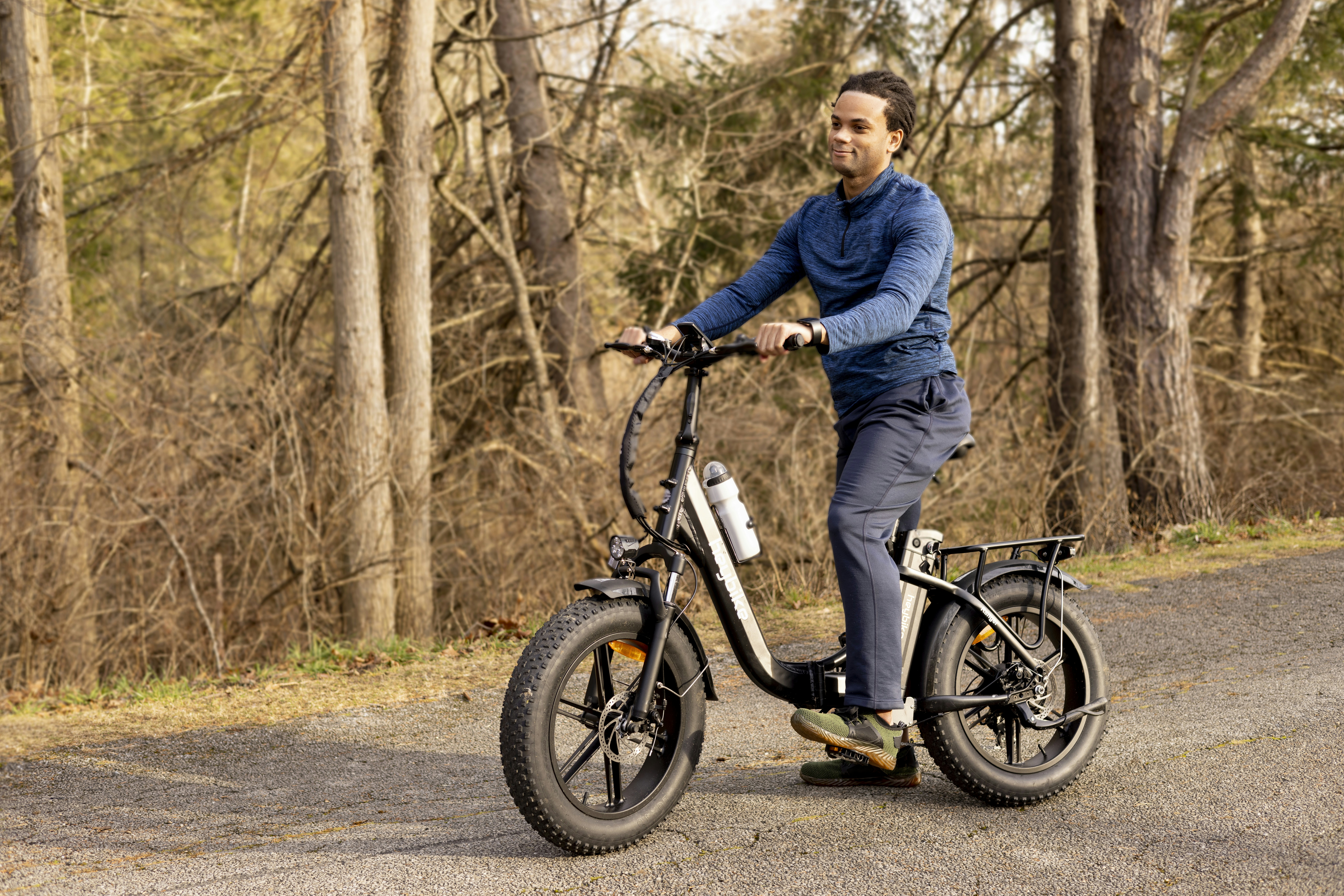 a man riding a bike down a road next to a forest