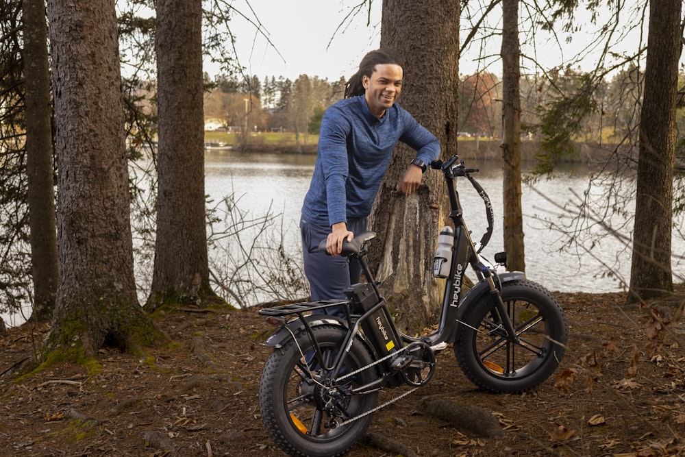 a man standing next to a bike in the woods