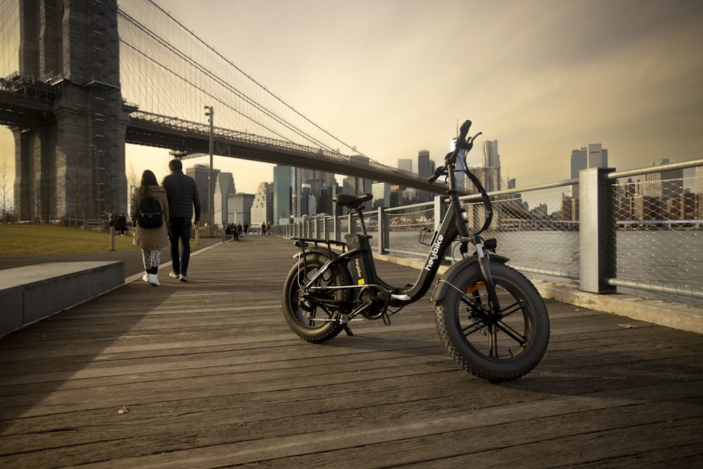 a bicycle is parked on a boardwalk near a bridge