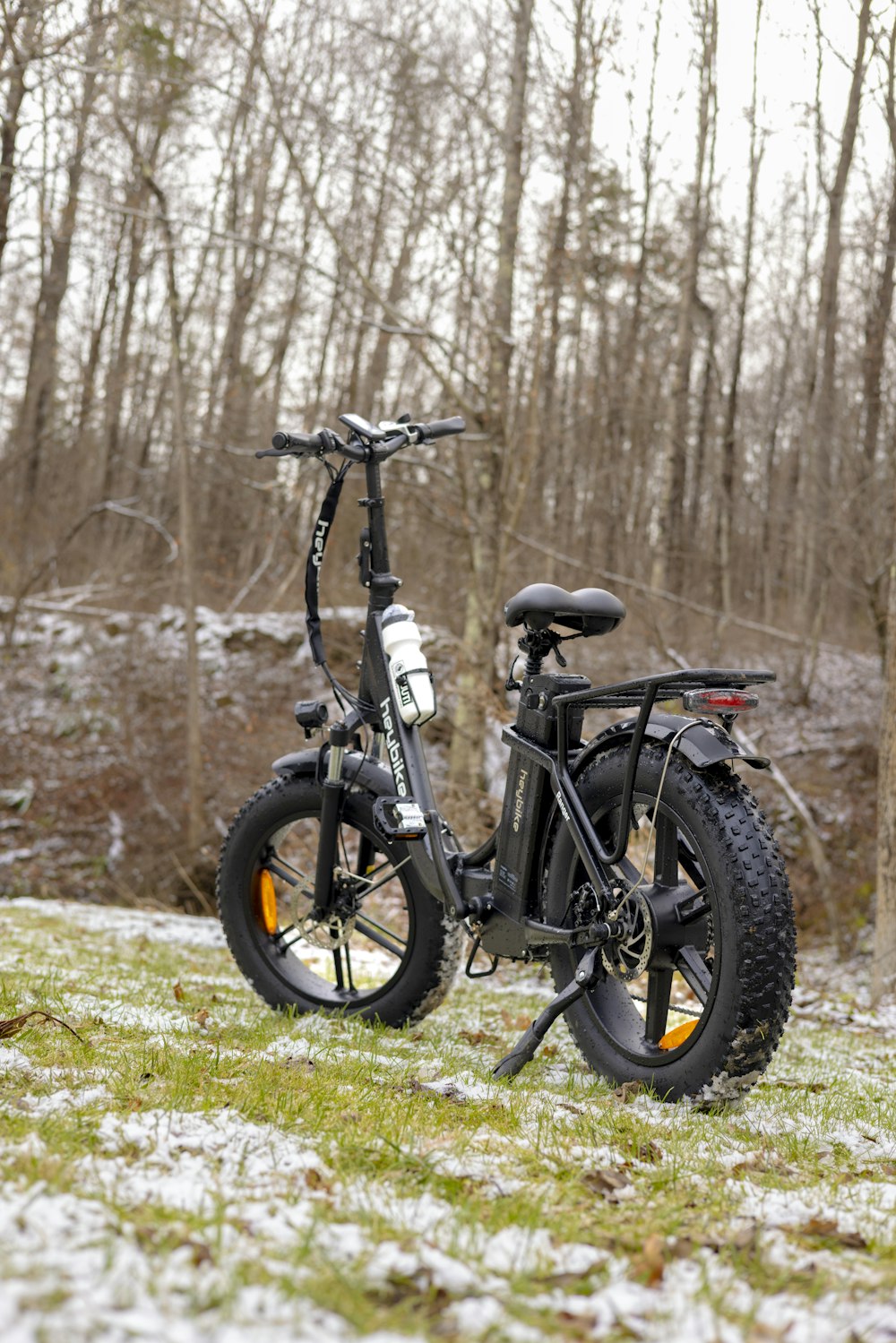 a bicycle parked in the grass in front of some trees