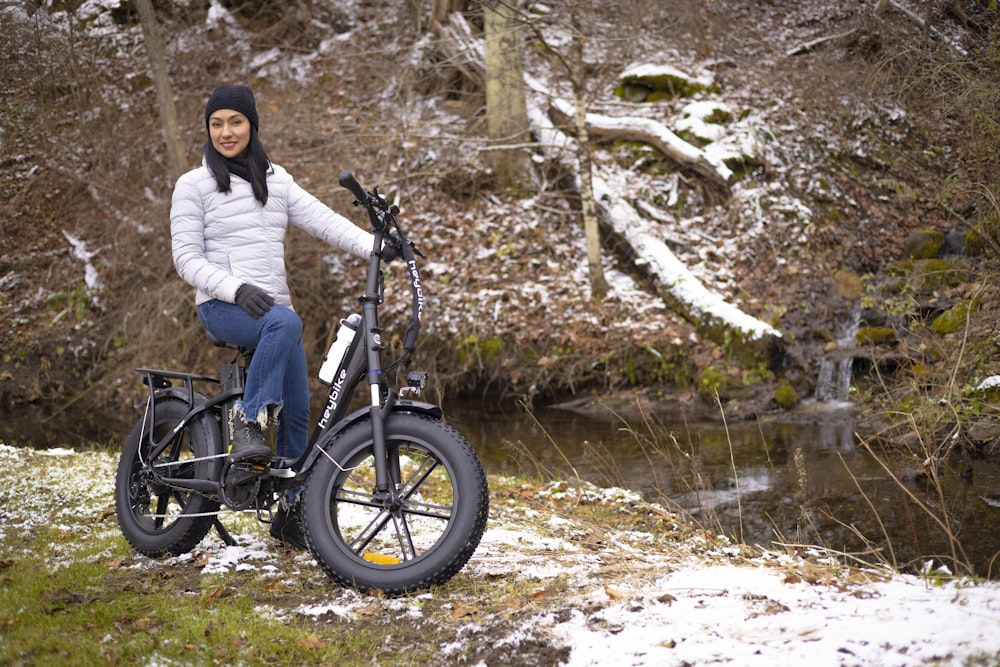 a woman sitting on top of a bike next to a river