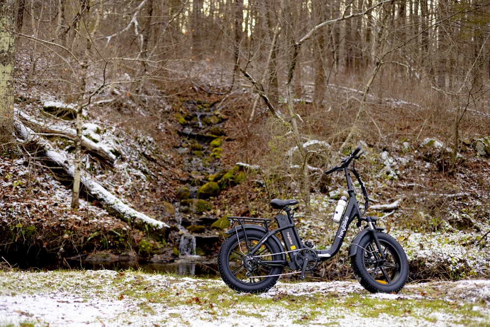 a bike parked in the snow in a wooded area