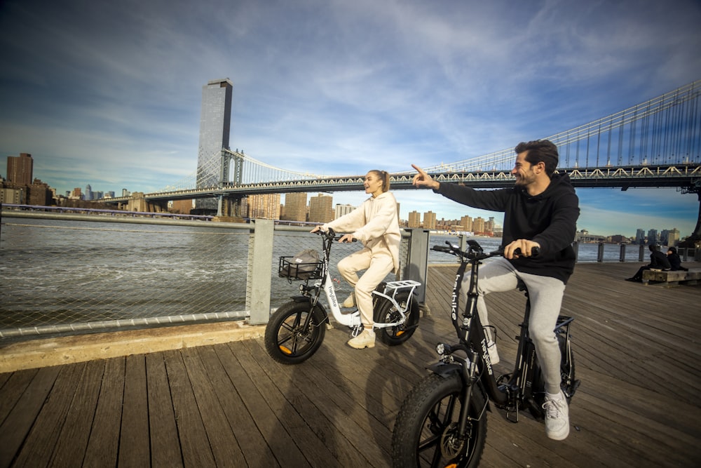 a man and a woman riding bikes on a pier