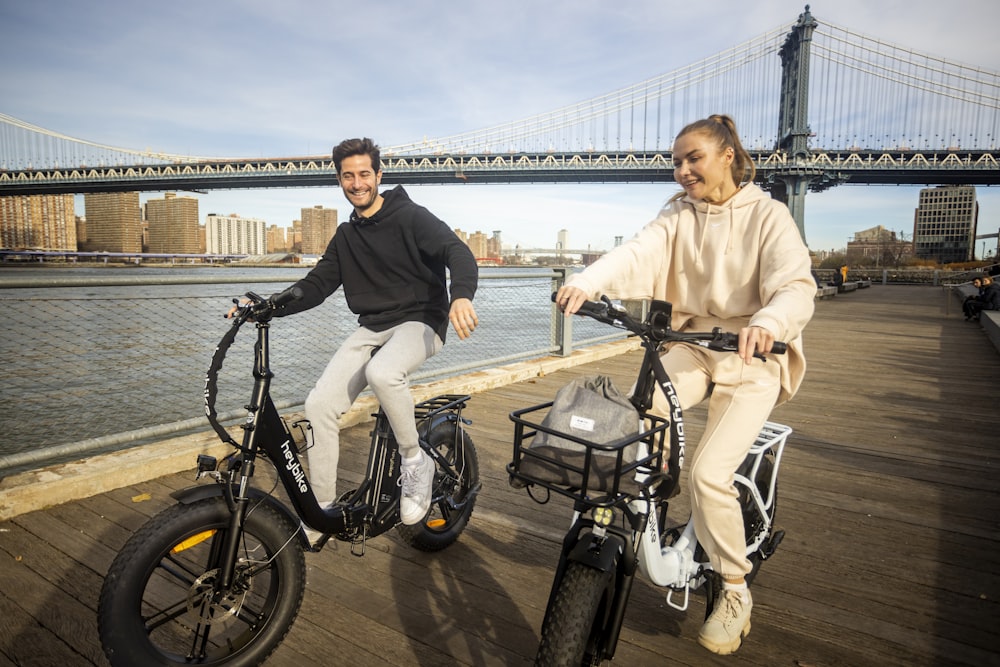 a man and a woman riding bikes on a pier