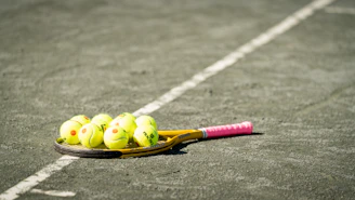 a tennis racket and four tennis balls on a tennis court