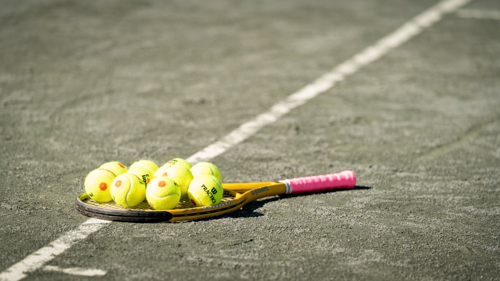 a tennis racket and four tennis balls on a tennis court
