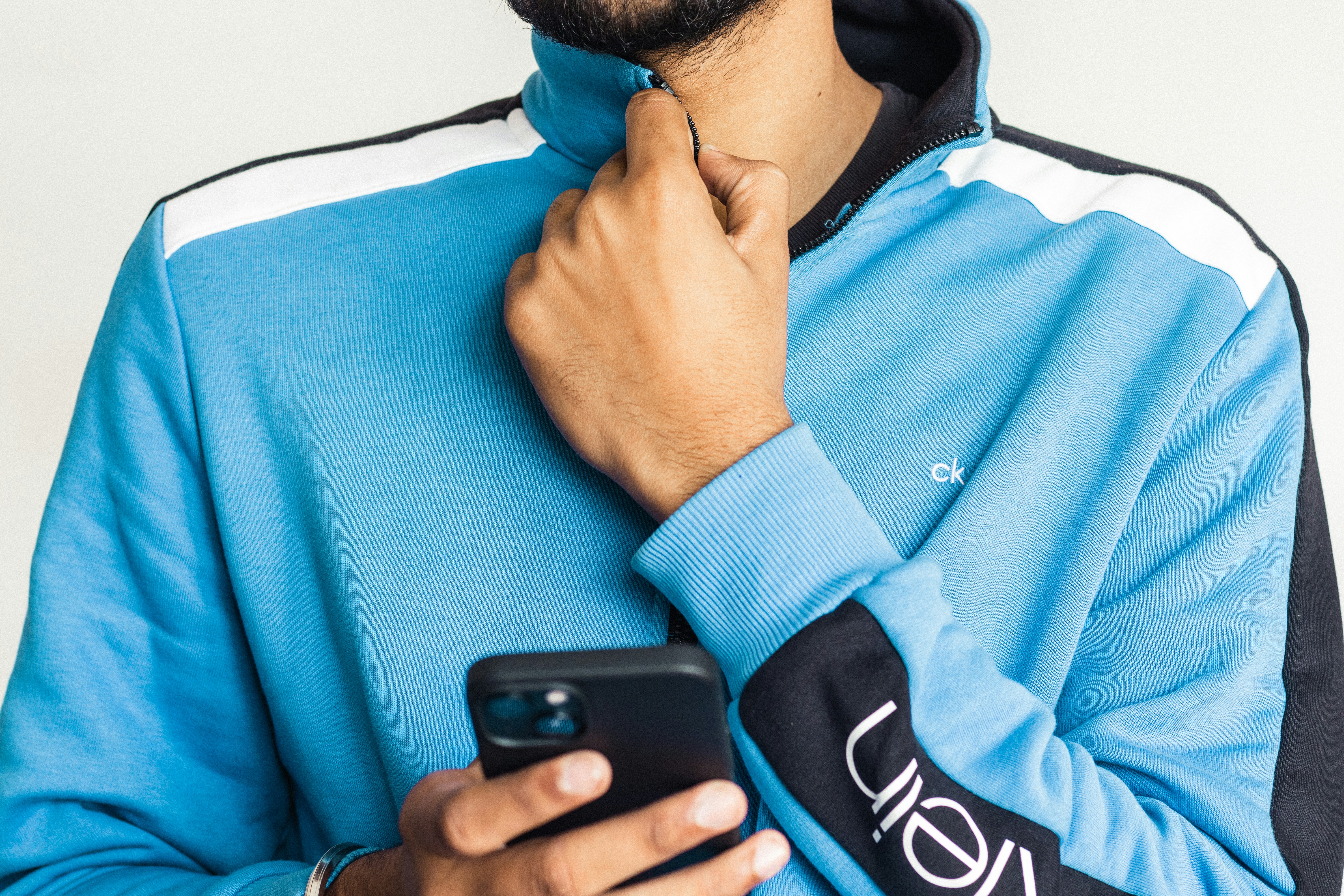 a man in a blue hoodie holding a cell phone