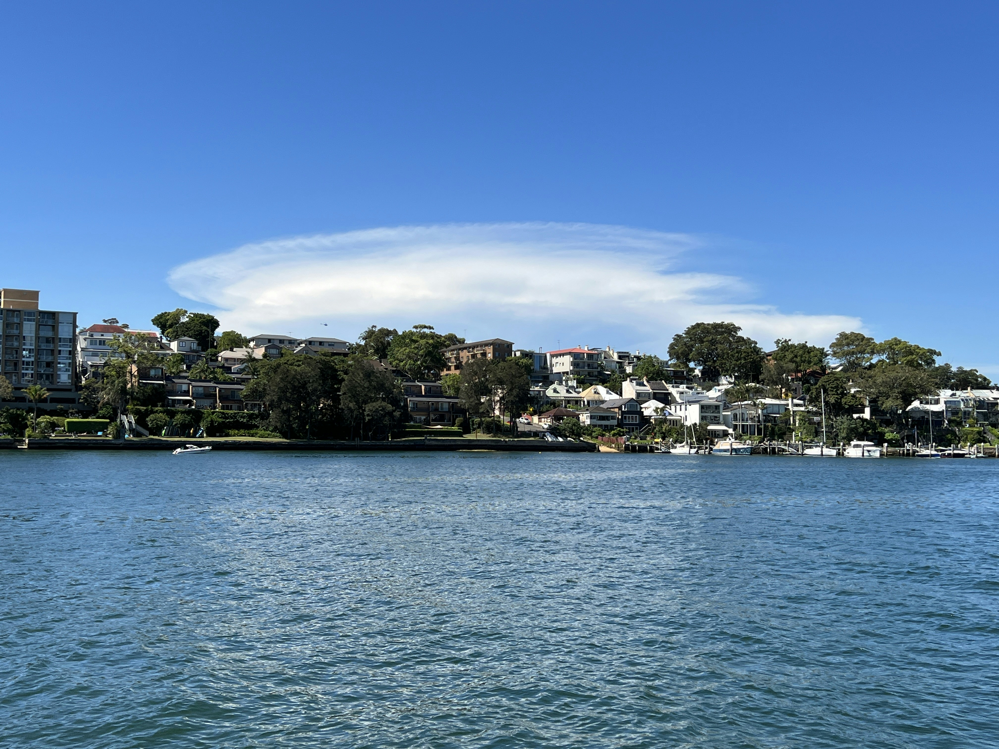 a body of water with houses on a hill in the background