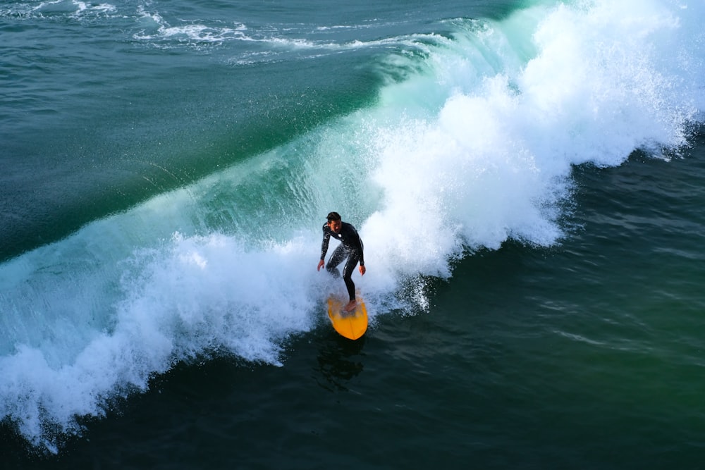 um homem cavalgando uma onda em cima de uma prancha de surf