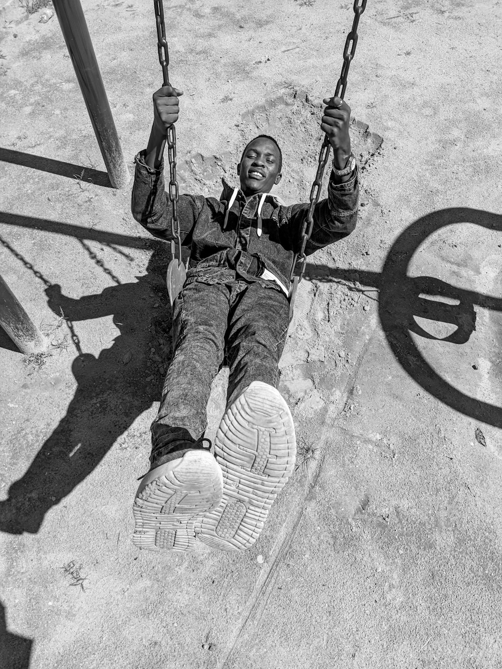 um homem sentado em um balanço em um playground