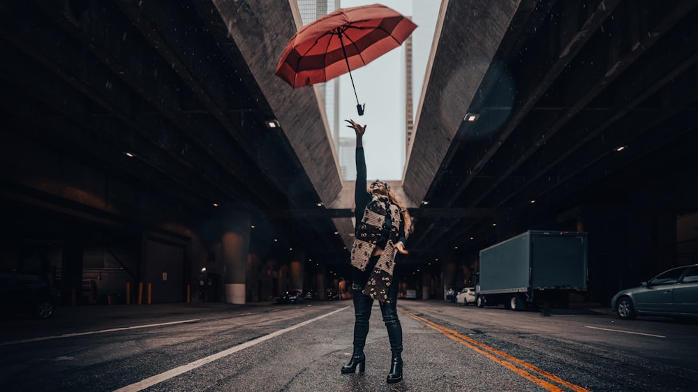 a woman holding an umbrella in the middle of a street