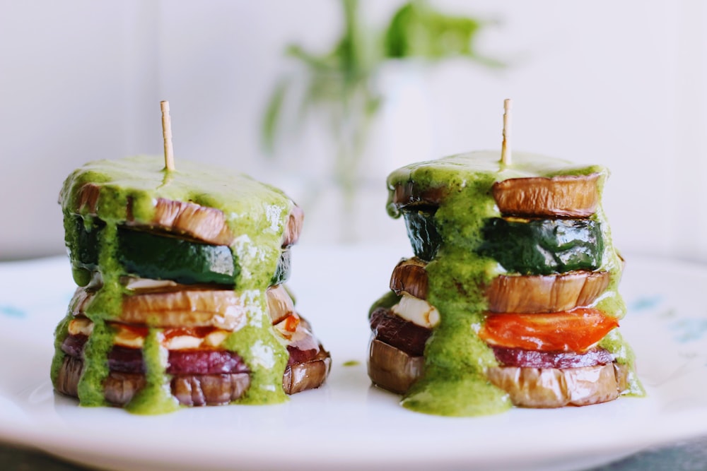 a white plate topped with sandwiches covered in green sauce
