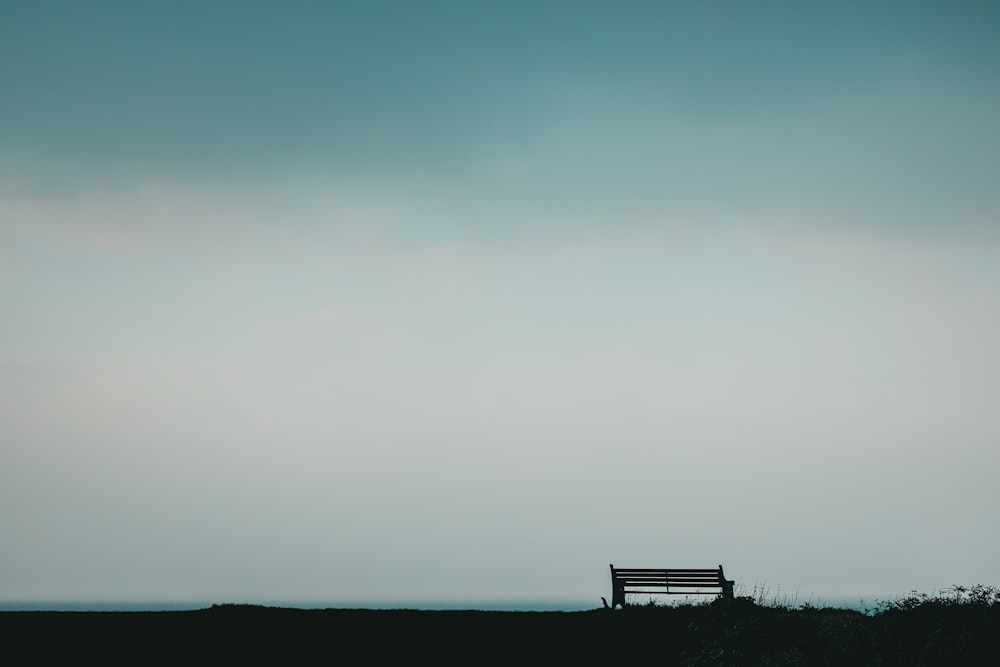 a bench sitting on top of a grass covered field