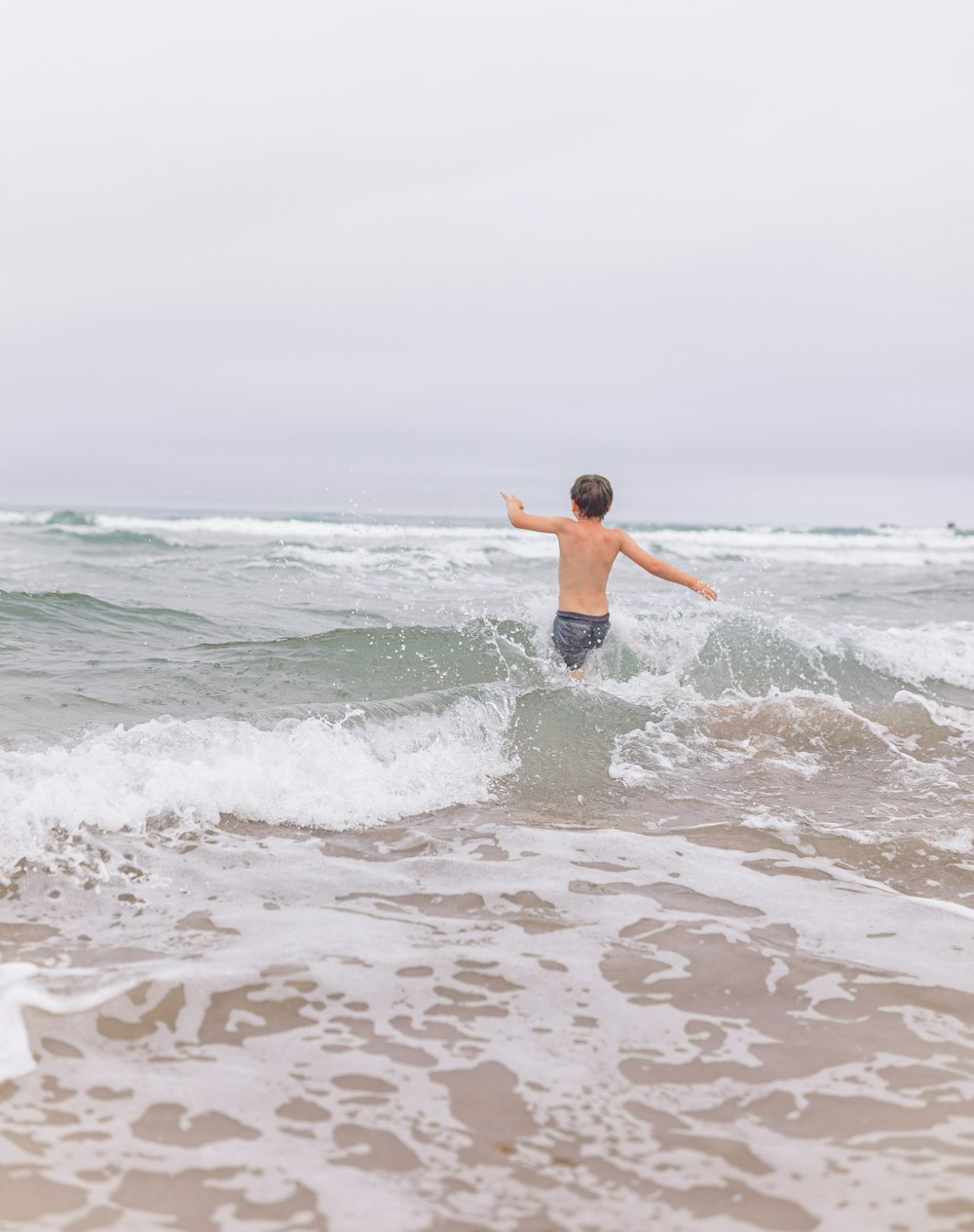 a young boy standing on a surfboard in the ocean