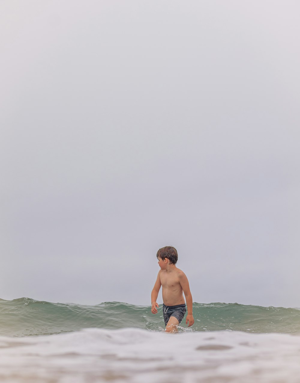 a young boy standing on a surfboard in the ocean