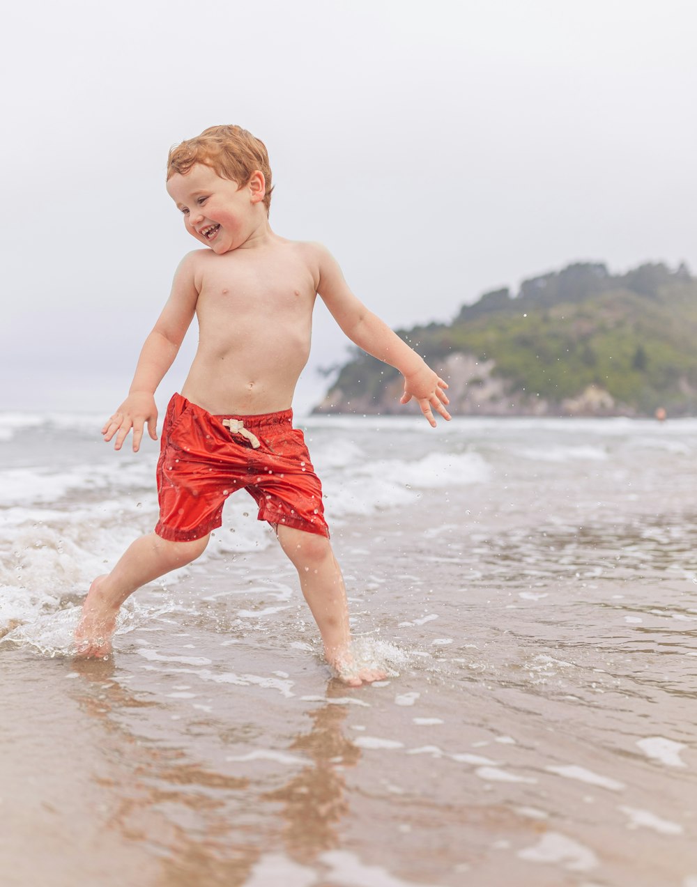 a young boy is playing in the water at the beach