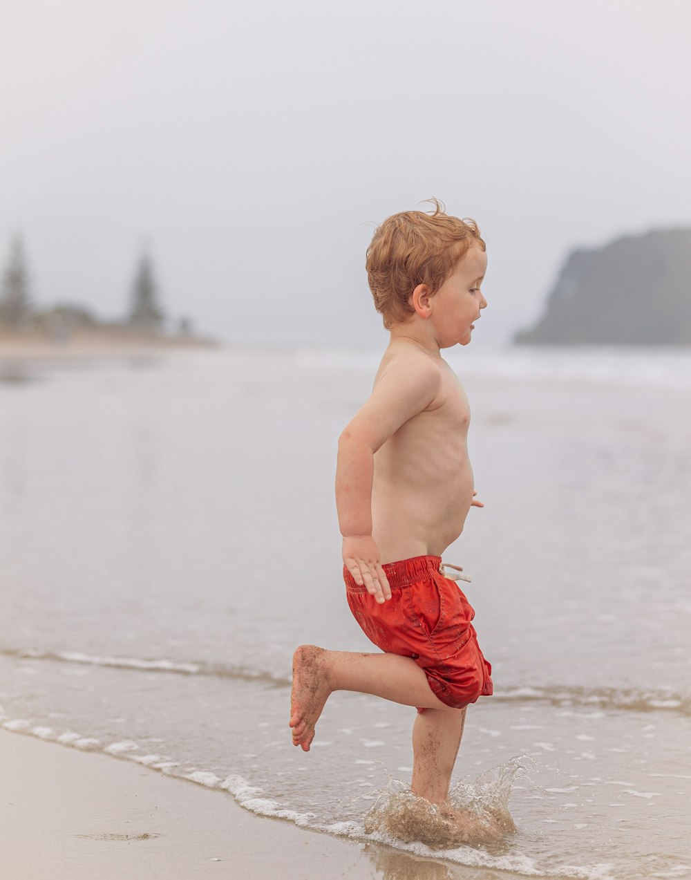 a young boy is running on the beach